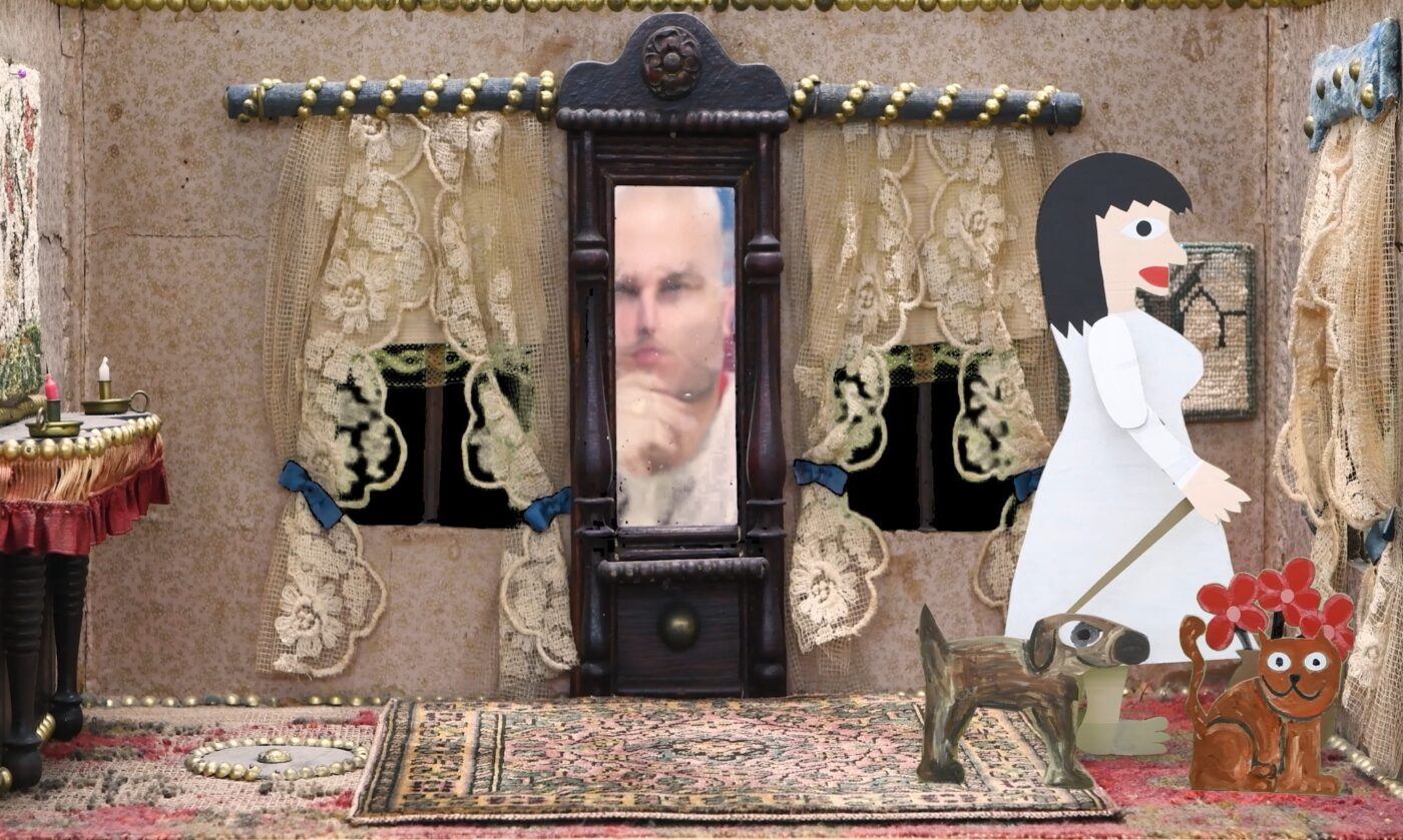 A handmade diorama shows a paper woman with a dog in a room with lace curtains, a rug, and a mirror reflecting a distorted man's face.