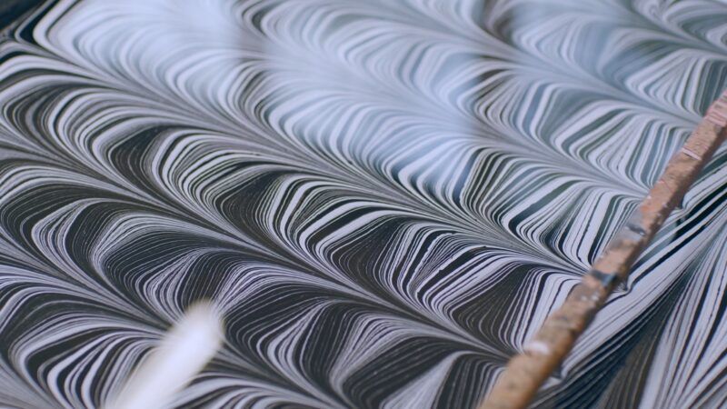 Close-up of detailed black and white striped patterns in a paper marbling tray.