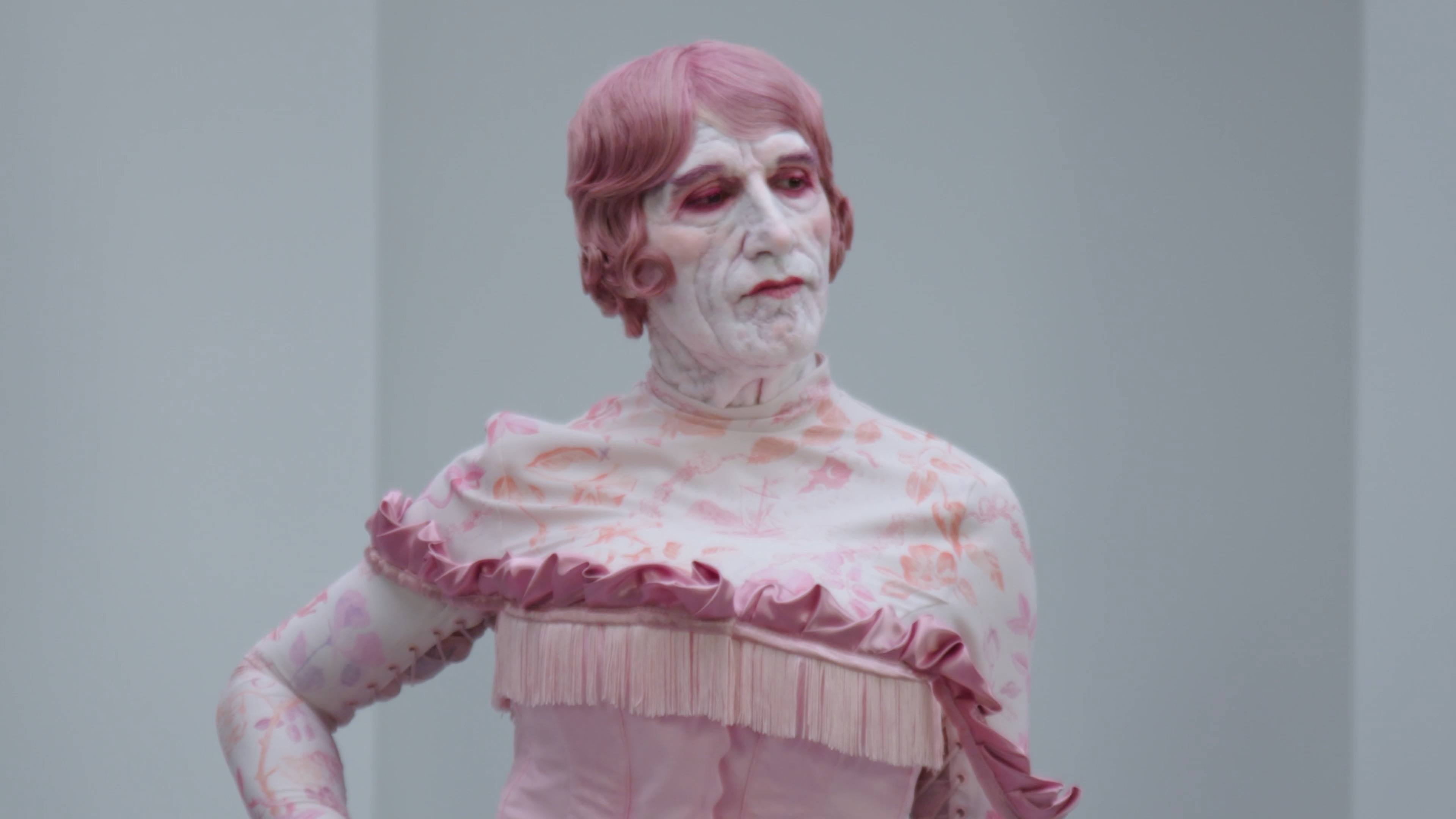 Alex Da Corted dress as Rrose Sélavy, wearing a pink wig and facial prosthetics.