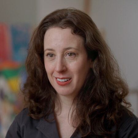 Aliza Nisenbaum with long brown hair, wearing a black shirt.